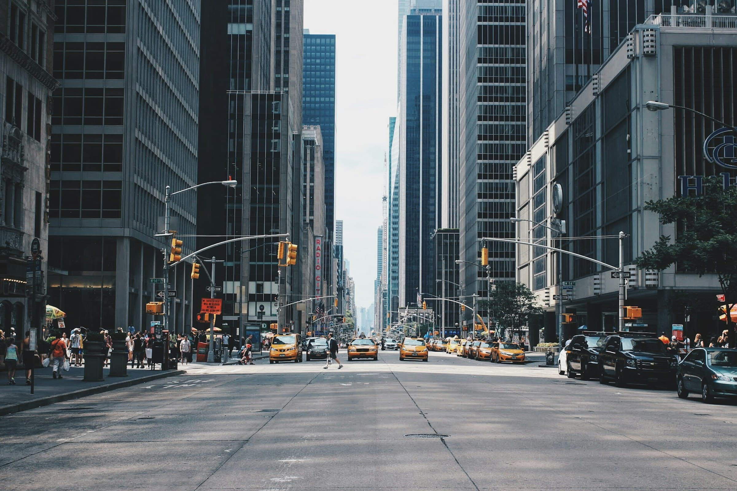 A wide midtown avenue with yellow cabs moving between tall buildings